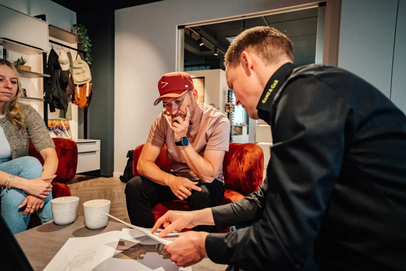 Drei Personen besprechen Bildmaterial an einem Tisch im Showroom.